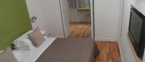 Quarto de hotel com cama, televisão e cabeceira verde.