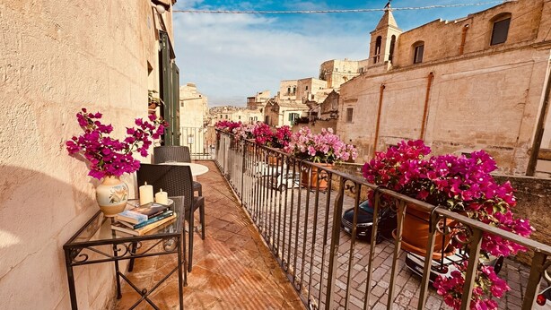 Un balcon avec une table, des chaises et des plantes en pot.