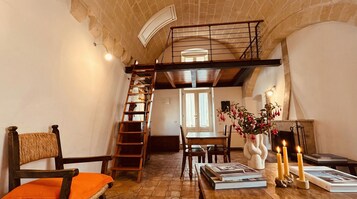 Una stanza accogliente con una scala in legno, un camino e libri su un tavolo.