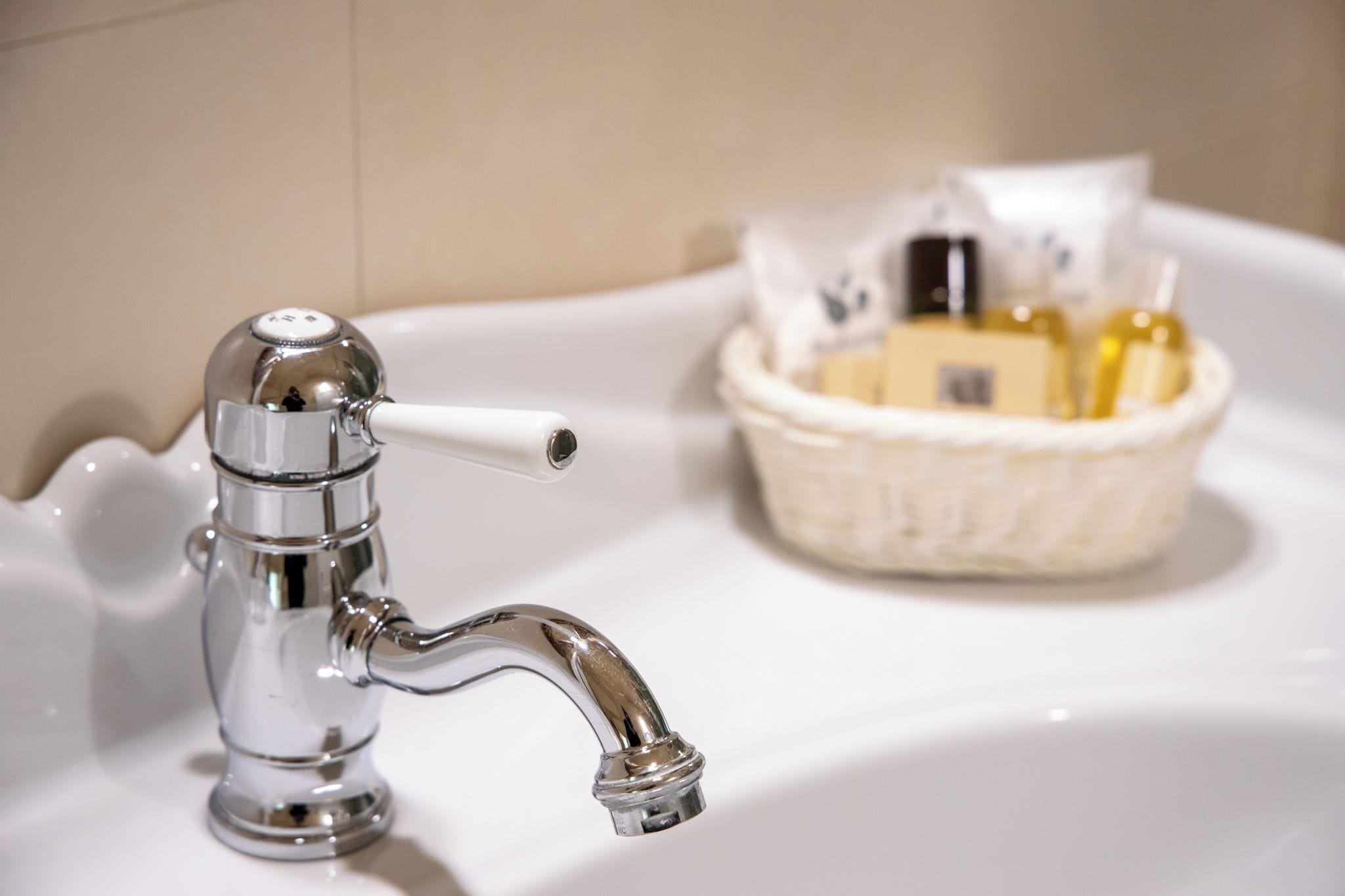Un lavandino da bagno con un rubinetto cromato e un portasapone.