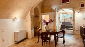 Un coin repas accueillant avec une table et des chaises, un vase de fleurs et une vue sur l’espace extérieur aménagé pour s’asseoir.