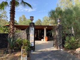 Uma entrada de pedra com uma placa para Vulcano Terme Residence, uma área de varanda coberta e um caminho que leva a um edifício.
