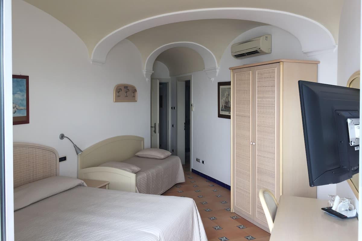 Une chambre d’hôtel avec deux lits, une télévision, une armoire et une porte donnant sur une autre pièce.