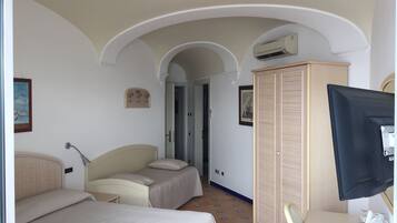 Una habitación de hotel con dos camas, televisión, armario y una puerta que da a otra habitación.