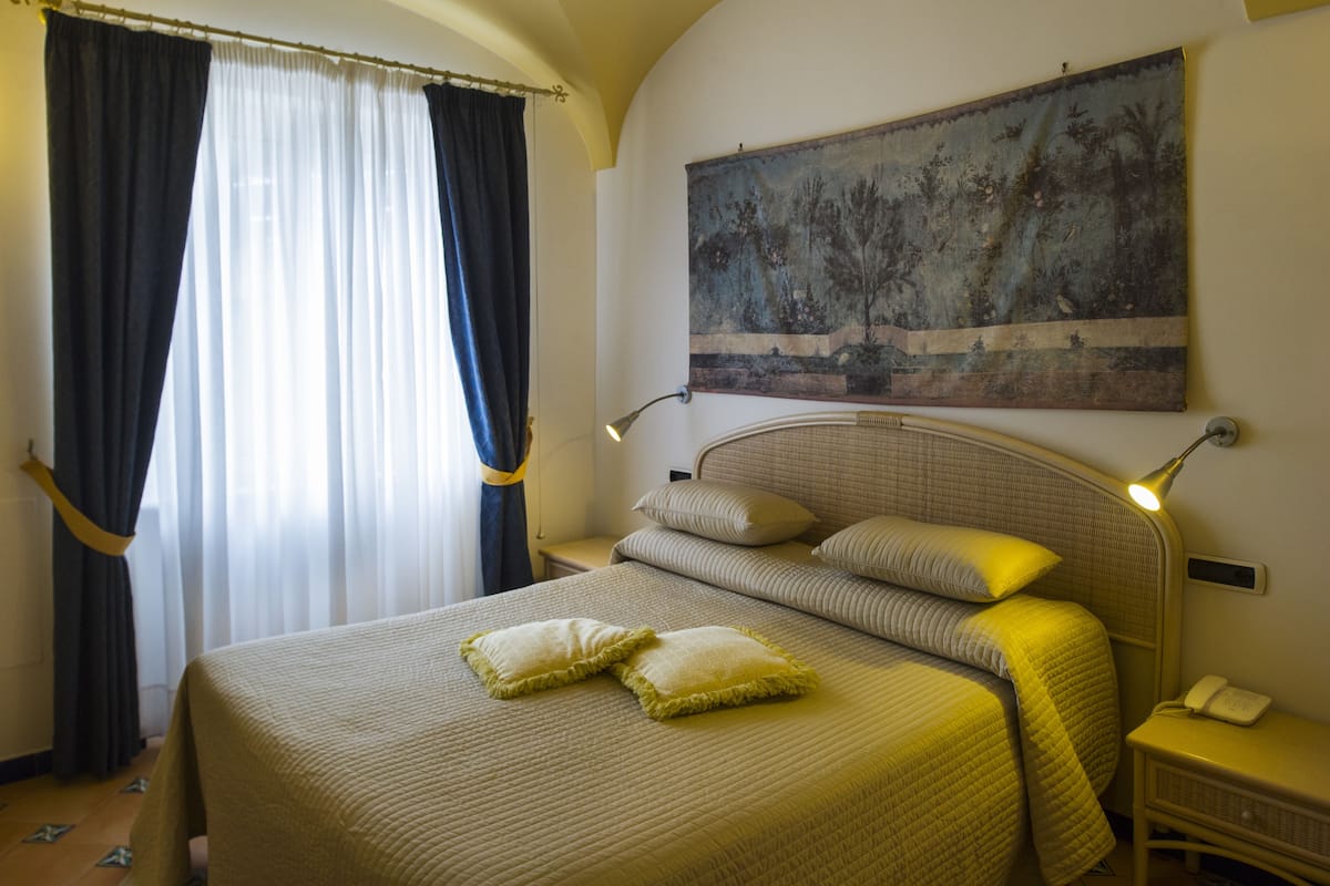 Une chambre d’hôtel avec un grand lit, deux oreillers, une lampe de chevet, une table de chevet et un tableau au mur.