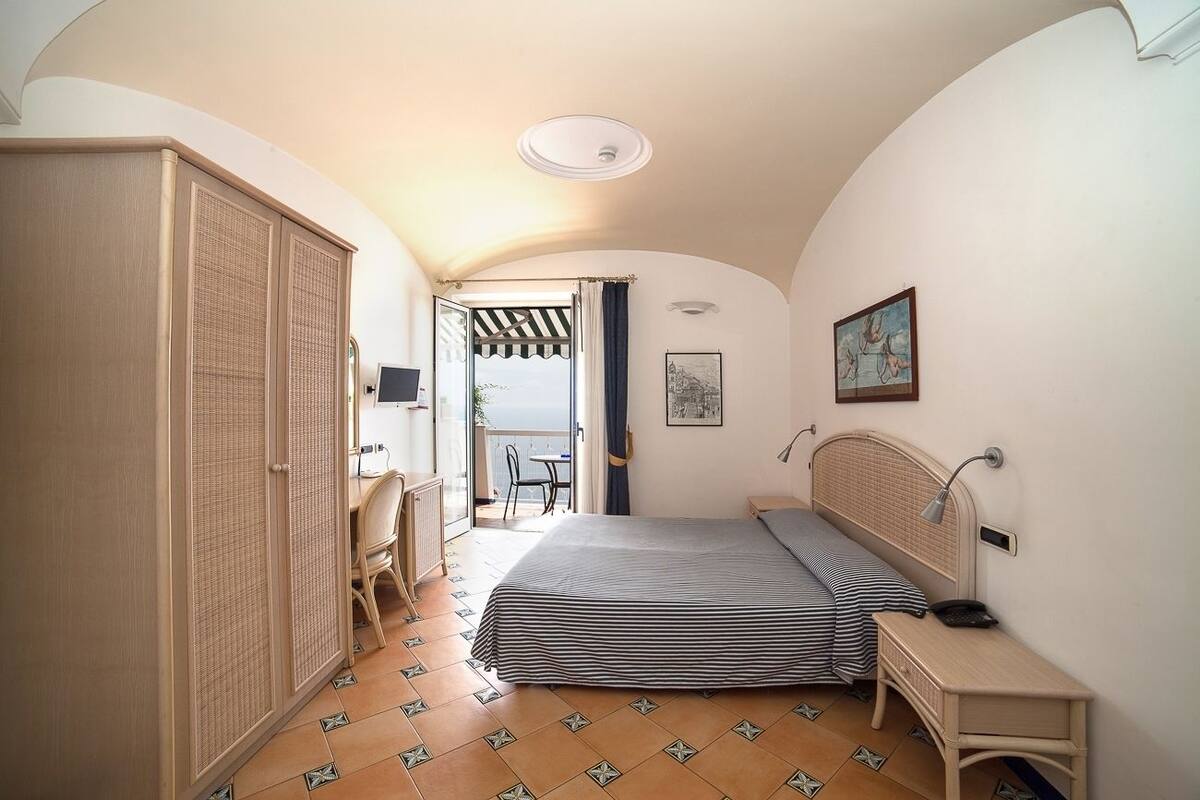 Une chambre avec un lit, un bureau et une armoire. Elle dispose d’un balcon avec vue.
