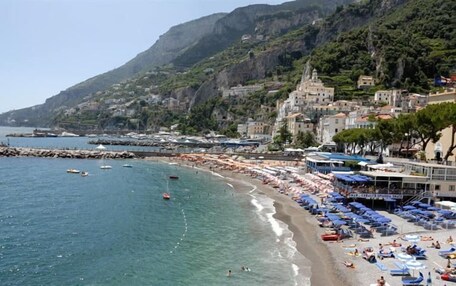 A coastal town with a beach, boats, and buildings along the shore.