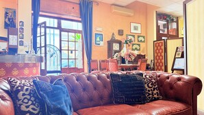 Un accogliente soggiorno con un divano in pelle marrone, un tavolo da pranzo con sedie e un'ampia finestra con tende.