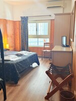 Una habitación con dos camas, un escritorio, una computadora, una silla y una ventana con cortinas.