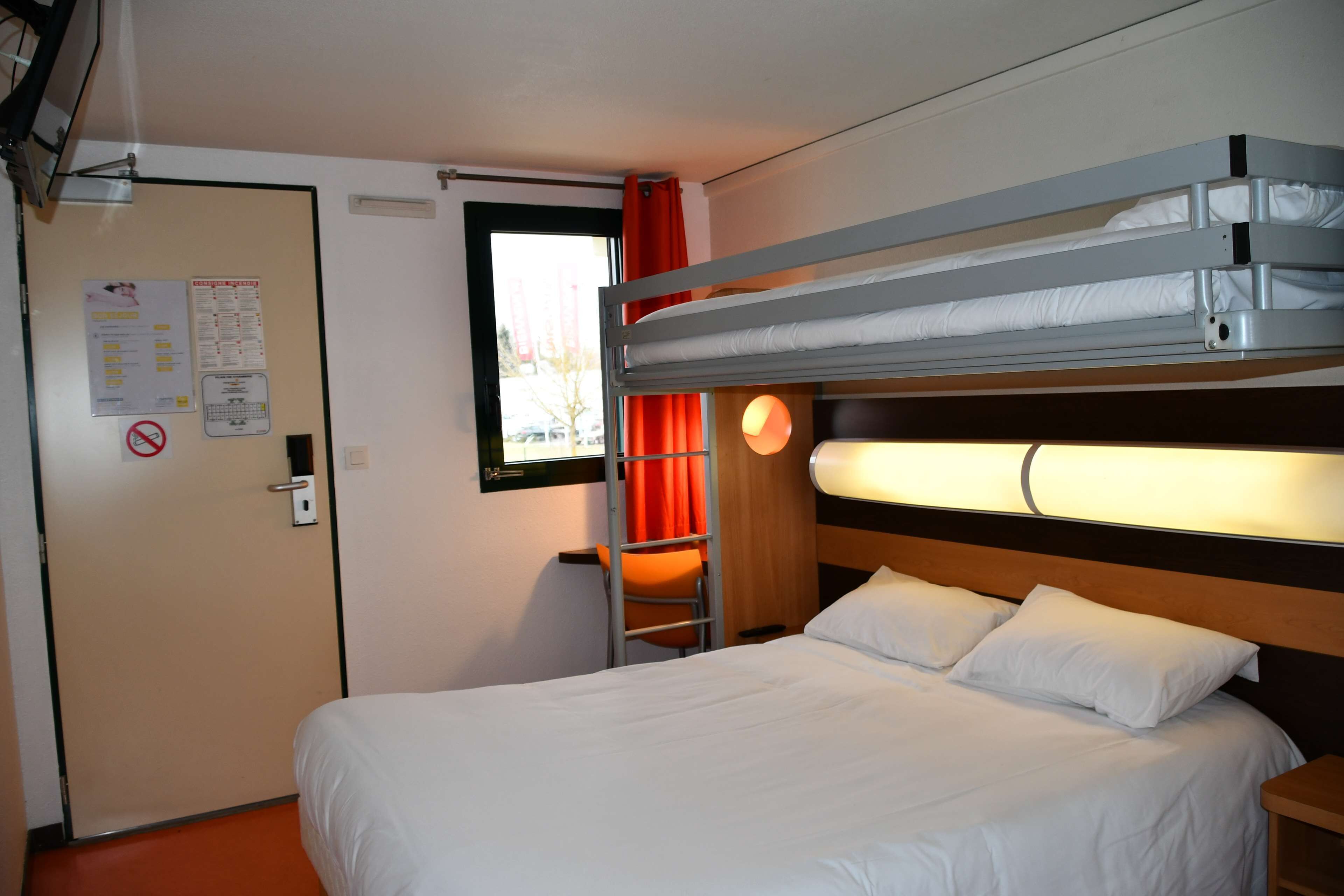 Una habitación de hotel con una cama litera, un escritorio y una silla.