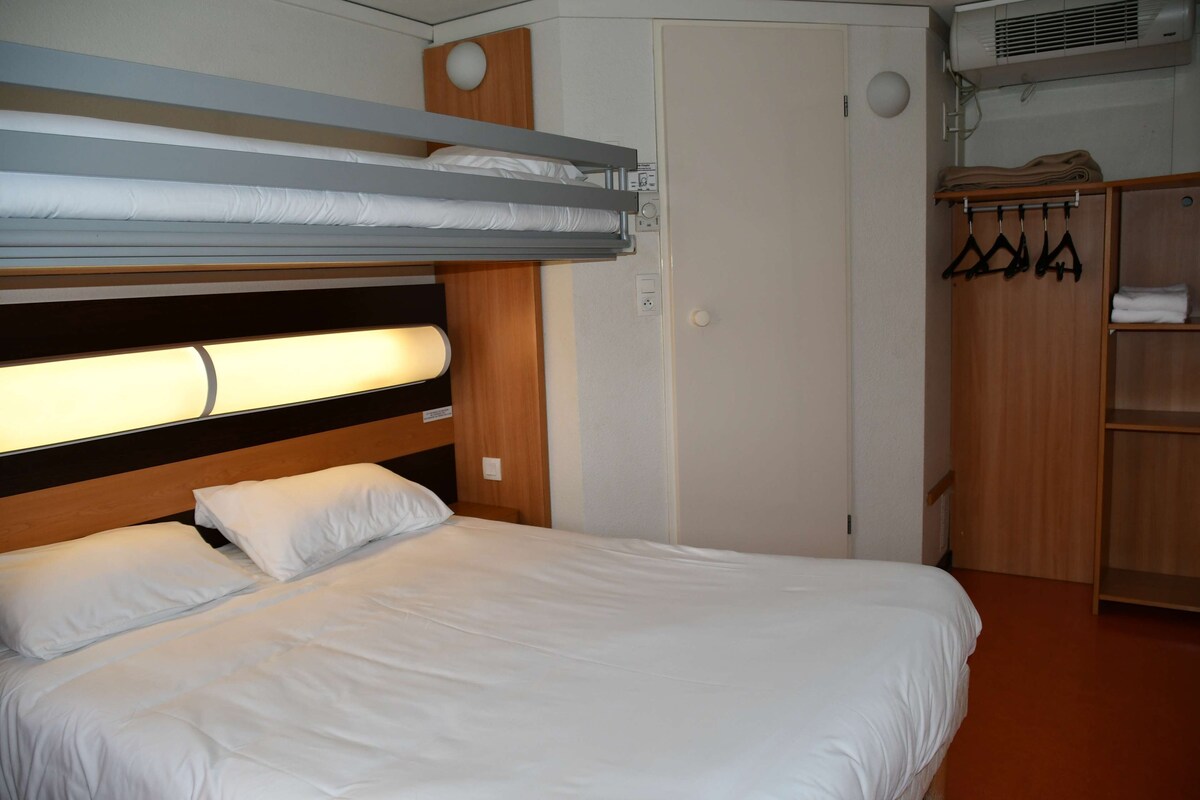 A bunk bed with a headboard, a wardrobe with hangers, and a small shelf.