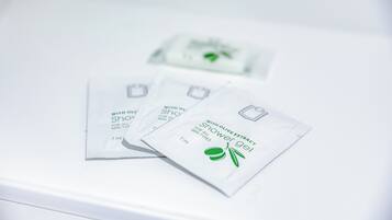 Three packets of shower gel with olive extract on a white surface.