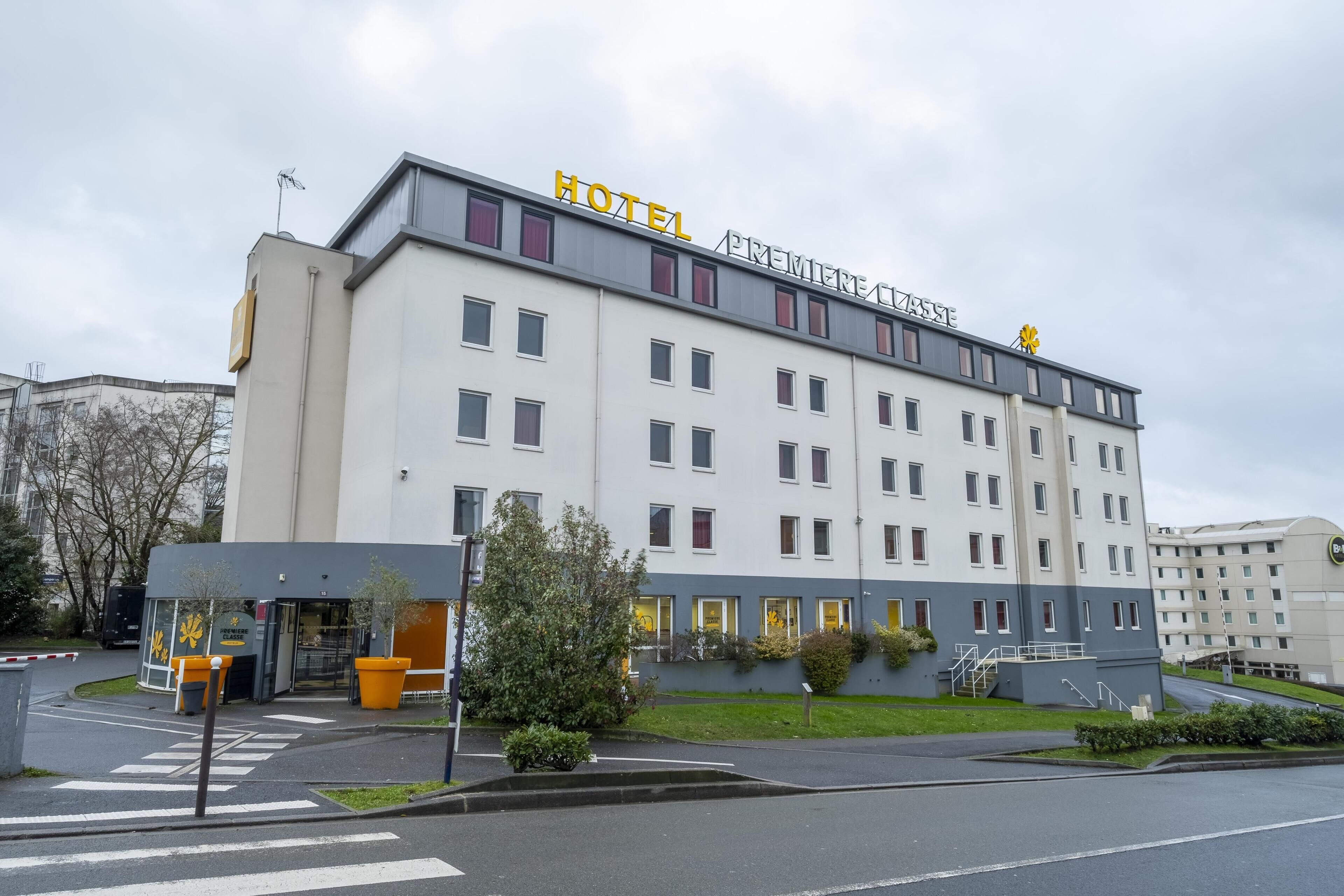 Un hôtel à plusieurs étages, doté d’un design moderne, et surmonté d’une grande enseigne « HOTEL PREMIERATZ » bien visible sur le toit.