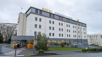 Un hôtel à plusieurs étages, doté d’un design moderne, et surmonté d’une grande enseigne « HOTEL PREMIERATZ » bien visible sur le toit.