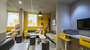 Una habitación con una decoración en tonos amarillo y gris, que incluye un sofá, una mesa y un televisor.