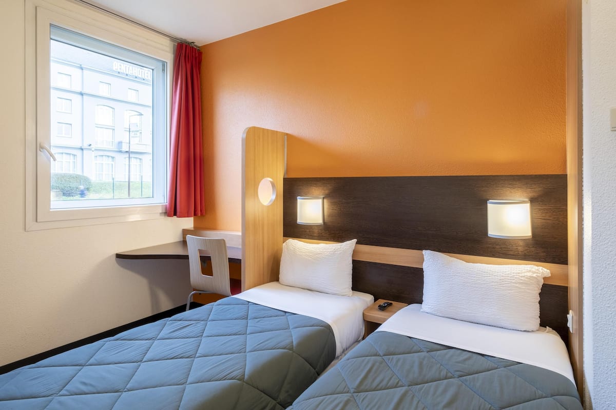 Ein Hotelzimmer mit zwei Betten, einem Schreibtisch und einem Stuhl.