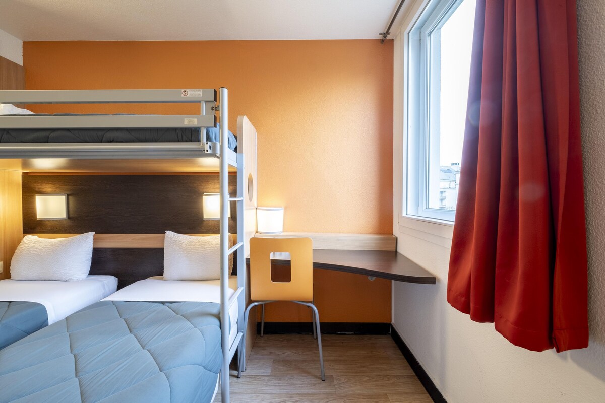 A hotel room with a bunk bed, a desk, and a chair.