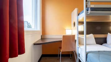 A bunk bed room with a desk and chair, a window with curtains, and a view of buildings outside.