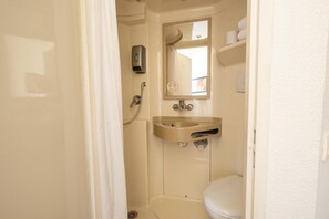 A small, compact bathroom with a toilet, a sink, and a shower. - Première Classe Roissy - Aéroport Charles De Gaulle (Roissy-en-France)