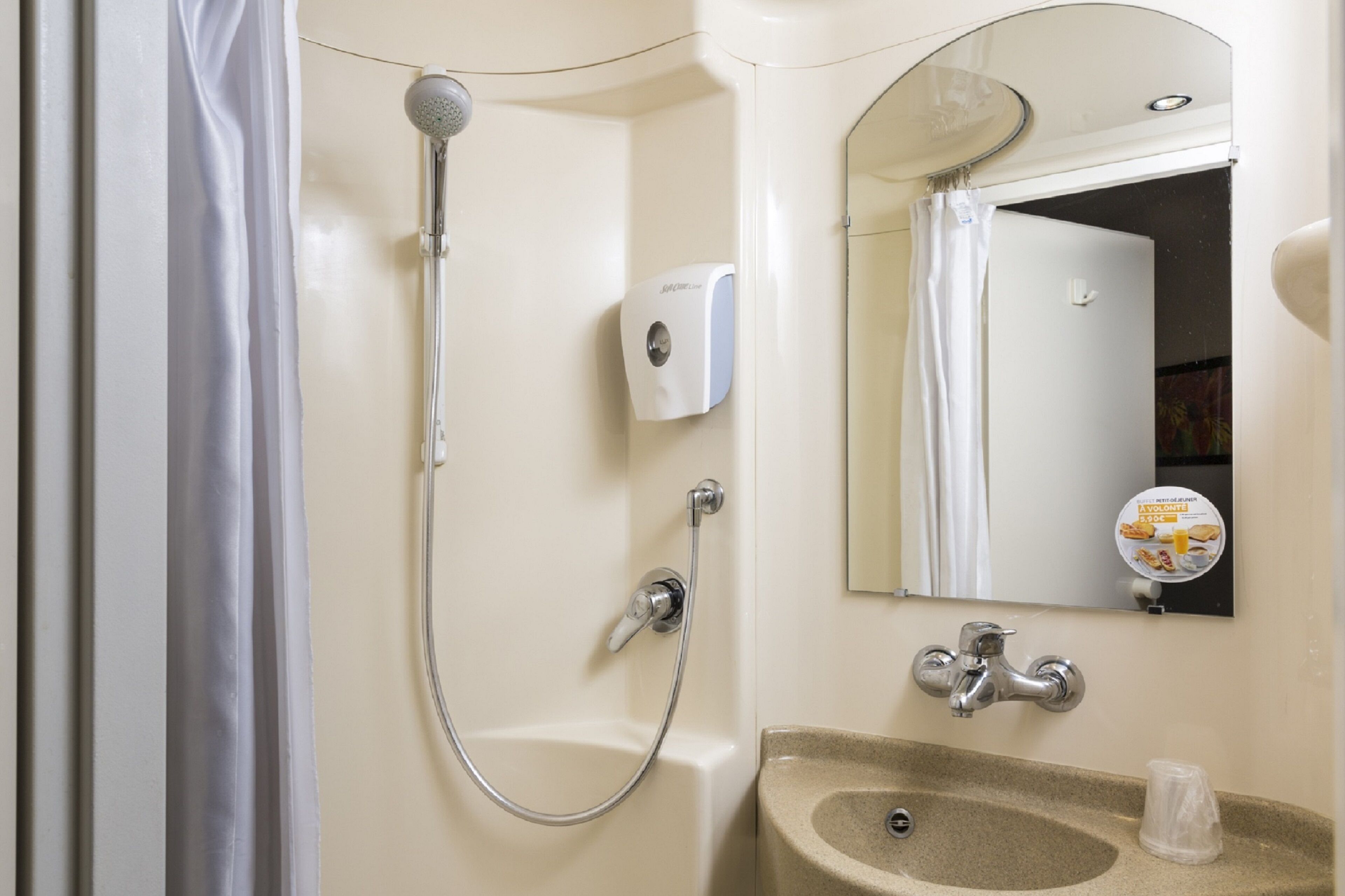 Un baño con ducha, lavamanos y espejo.