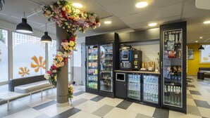 Un interior limpio y moderno con asientos, dispensadores de bebidas y una decoración floral.