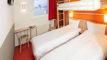 A hotel room with two beds, a desk, a chair, a radiator, and a window with curtains.