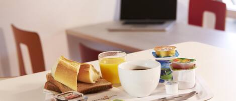 A breakfast tray with toast, juice, coffee, and yogurt on a hotel table.