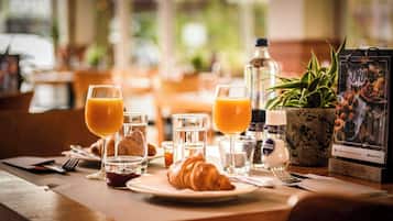 Guests can enjoy a meal at a dining table with a potted plant and a menu stand.