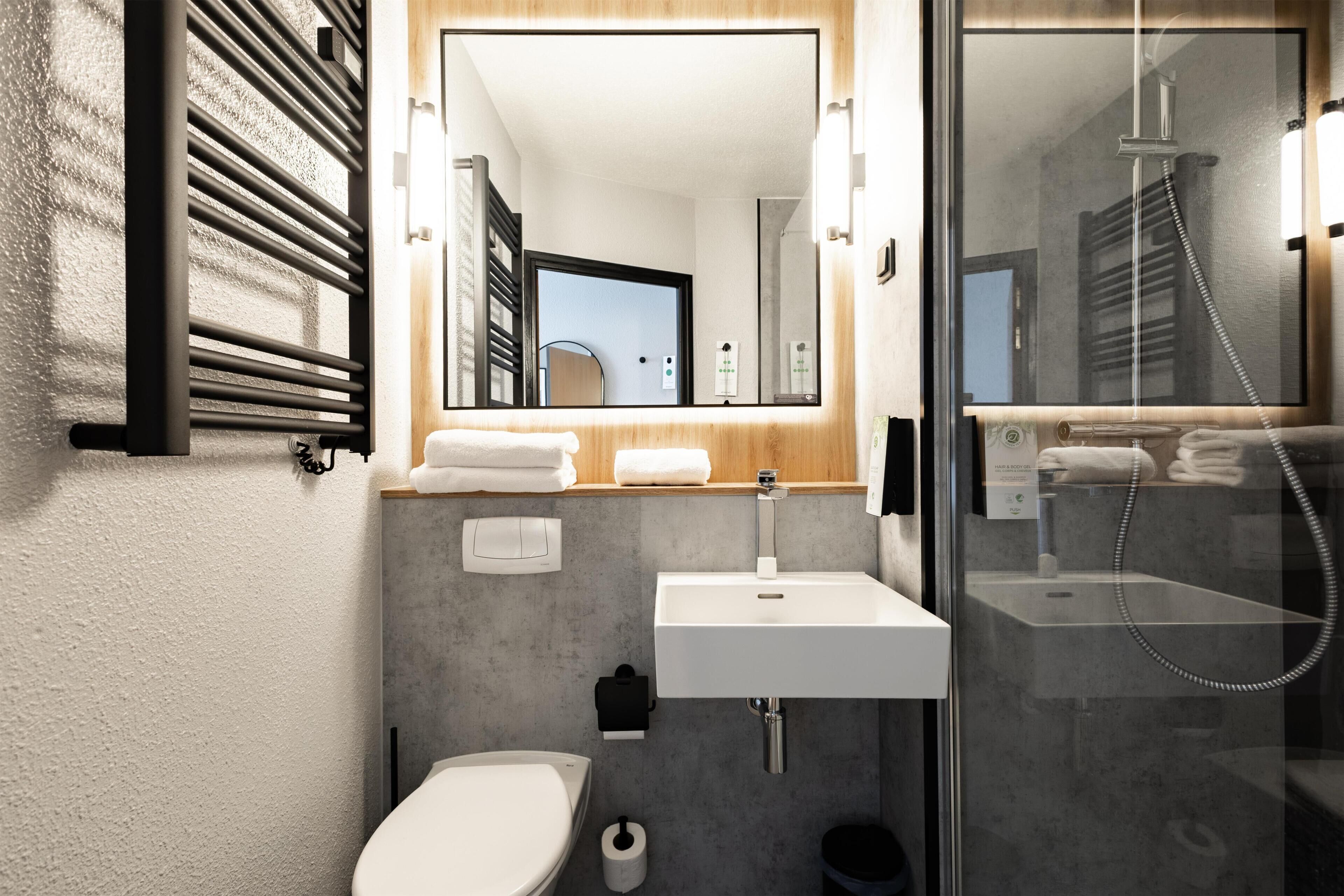 A modern bathroom with a toilet, sink, and shower.