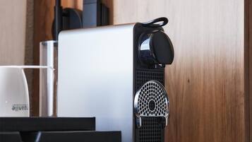 A coffee machine with a black and white design, a cup holder, and a coffee cup on a table.