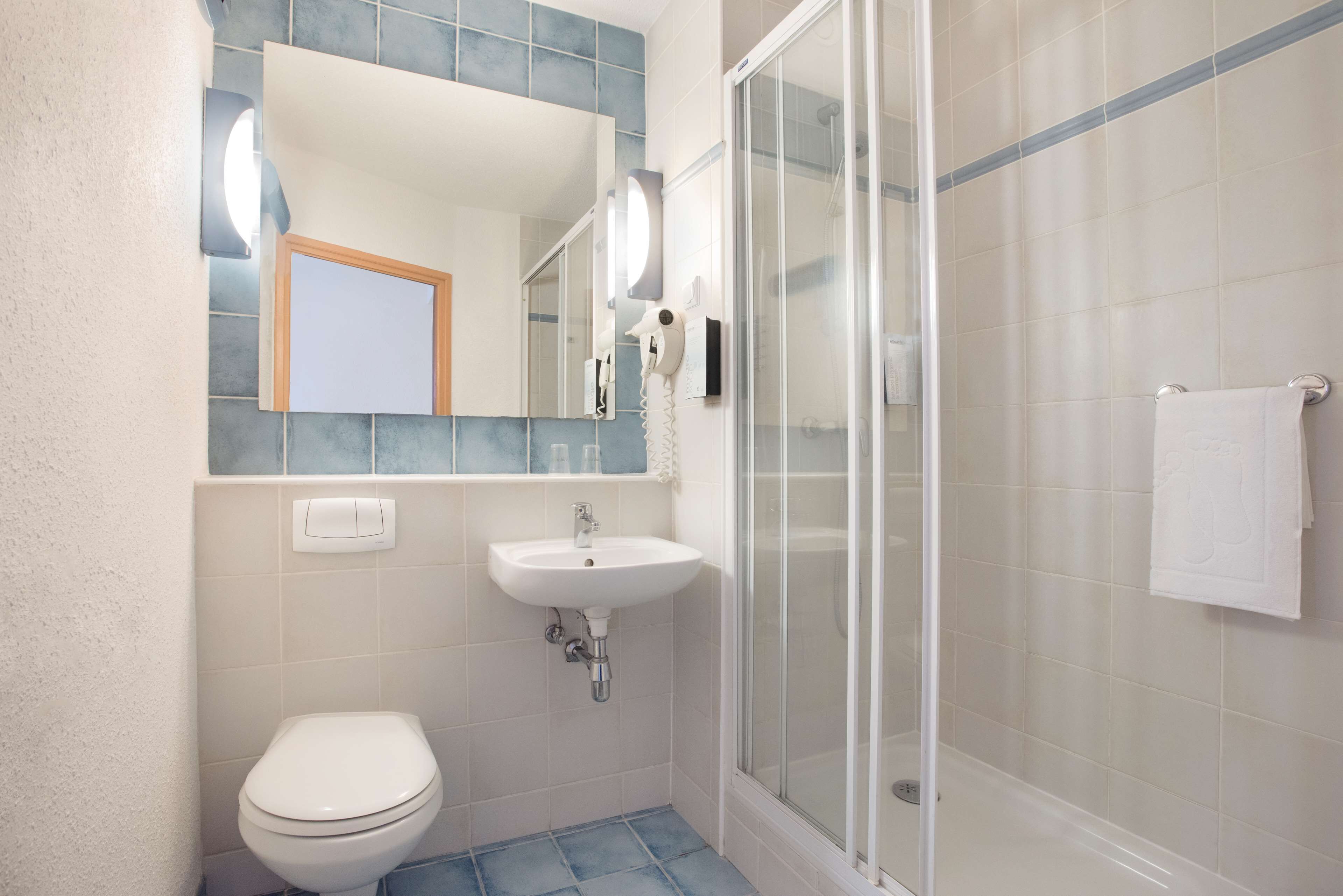 A bathroom with a toilet, sink, and glass-enclosed shower.