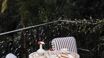 A round table with a white vase, a glass of water, a cup, and a plate with a slice of cake. There are striped chairs around the table.