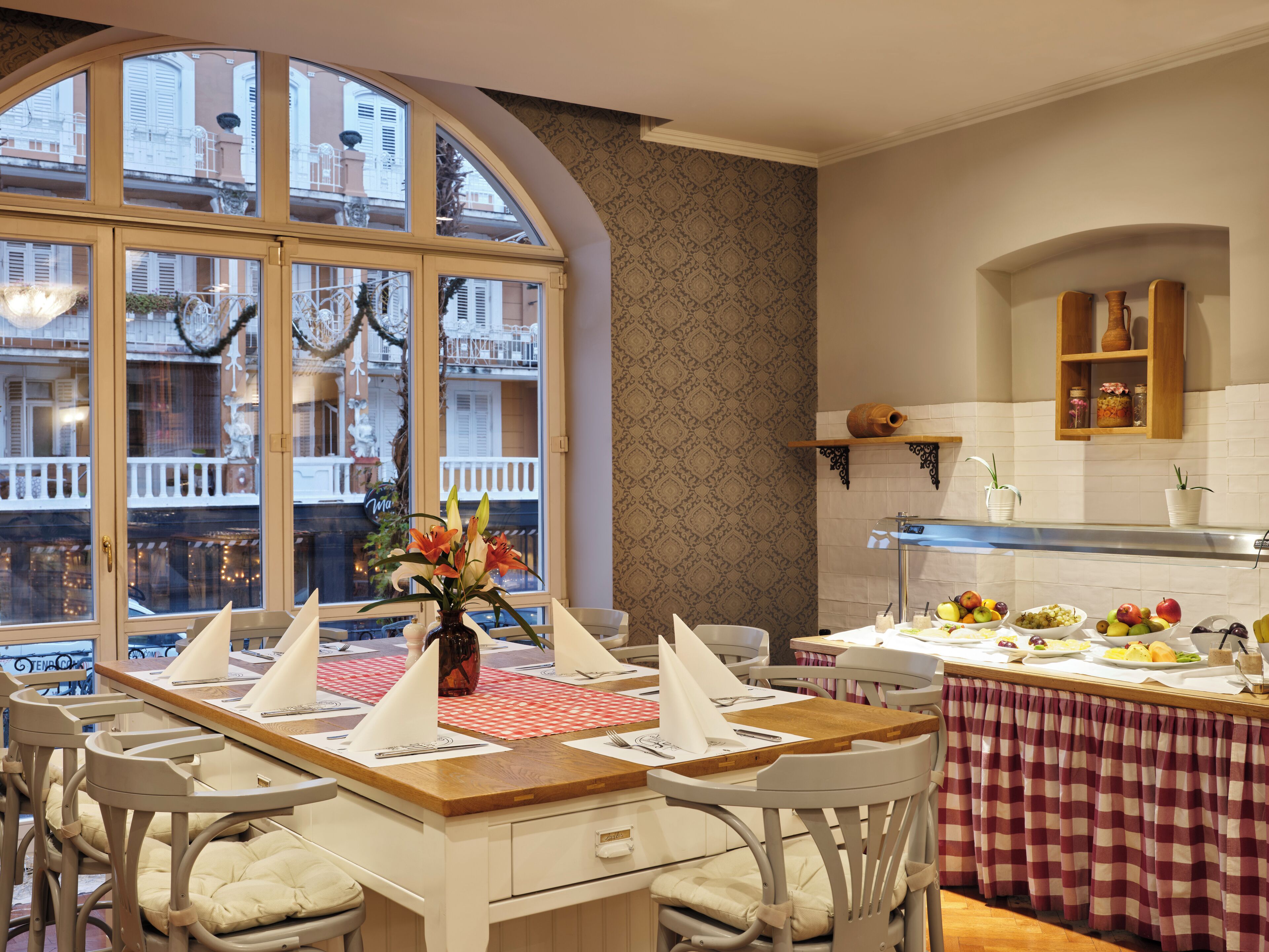 Ein Essbereich mit großem Fenster, einem Buffet mit Obst und Gemüse und Blick auf die Straße.