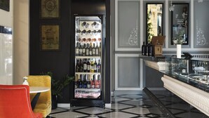 Una zona de bar con un mini refrigerador, una silla roja y un mantel a cuadros.