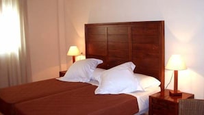 A double bed with white linens, two bedside tables with lamps, and a wooden headboard.