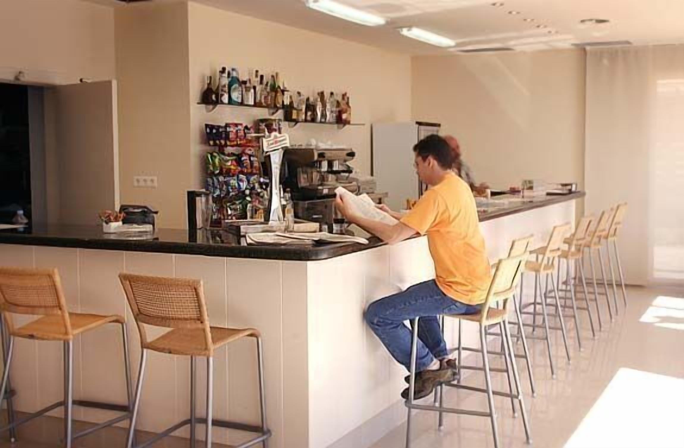 Una zona de bar con mostrador, taburetes y una variedad de botellas en estantes.