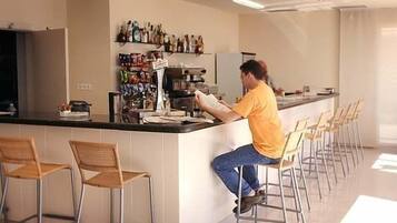 Una zona de bar con mostrador, taburetes y una variedad de botellas en estantes.