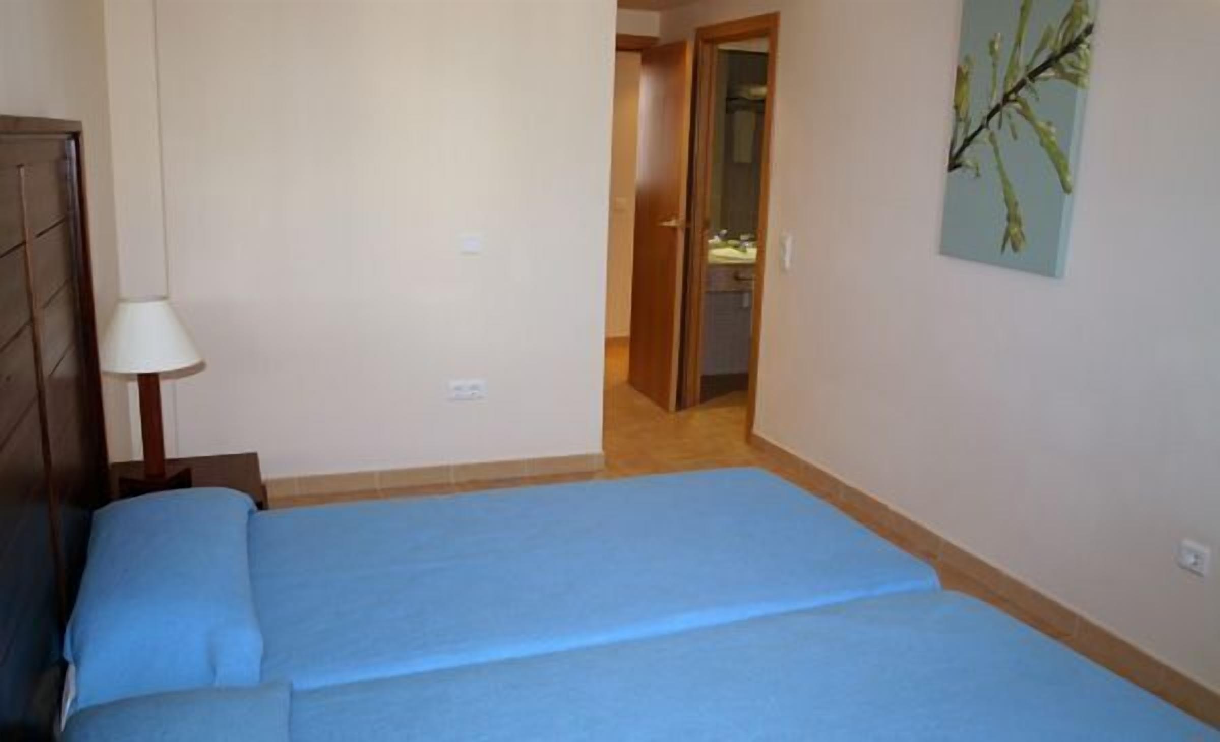 A room with a bed, a lamp, and a door leading to a bathroom.