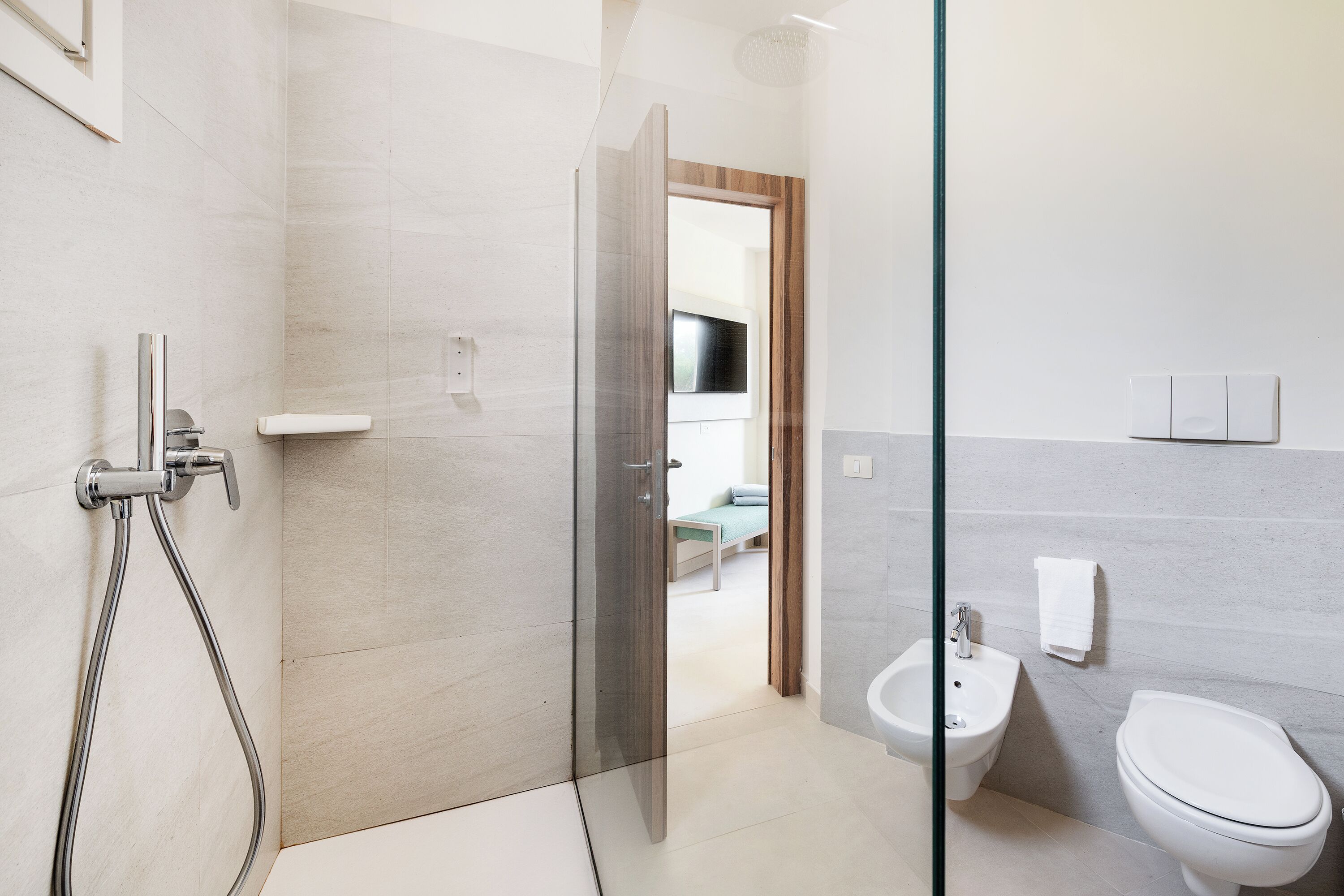 A modern bathroom with a glass shower enclosure, a bidet, and a toilet.