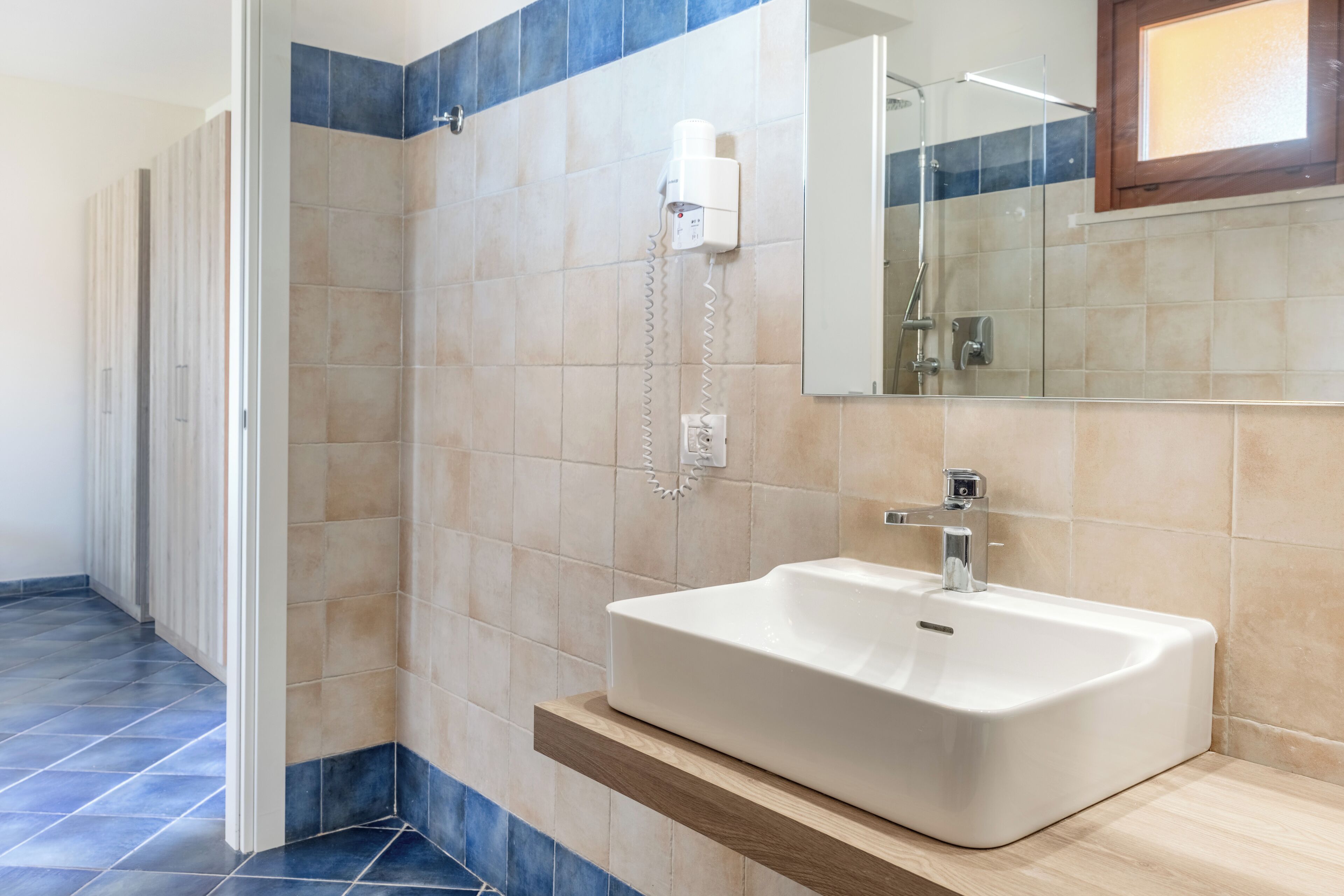 Un bagno con un lavandino bianco, uno specchio e uno spazio doccia.