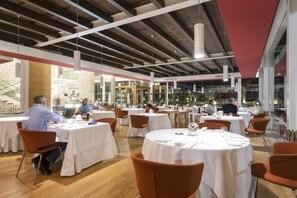A restaurant with round tables, orange chairs, and a modern interior with exposed beams and large windows. - Hotel Villa Carlotta (Ragusa)