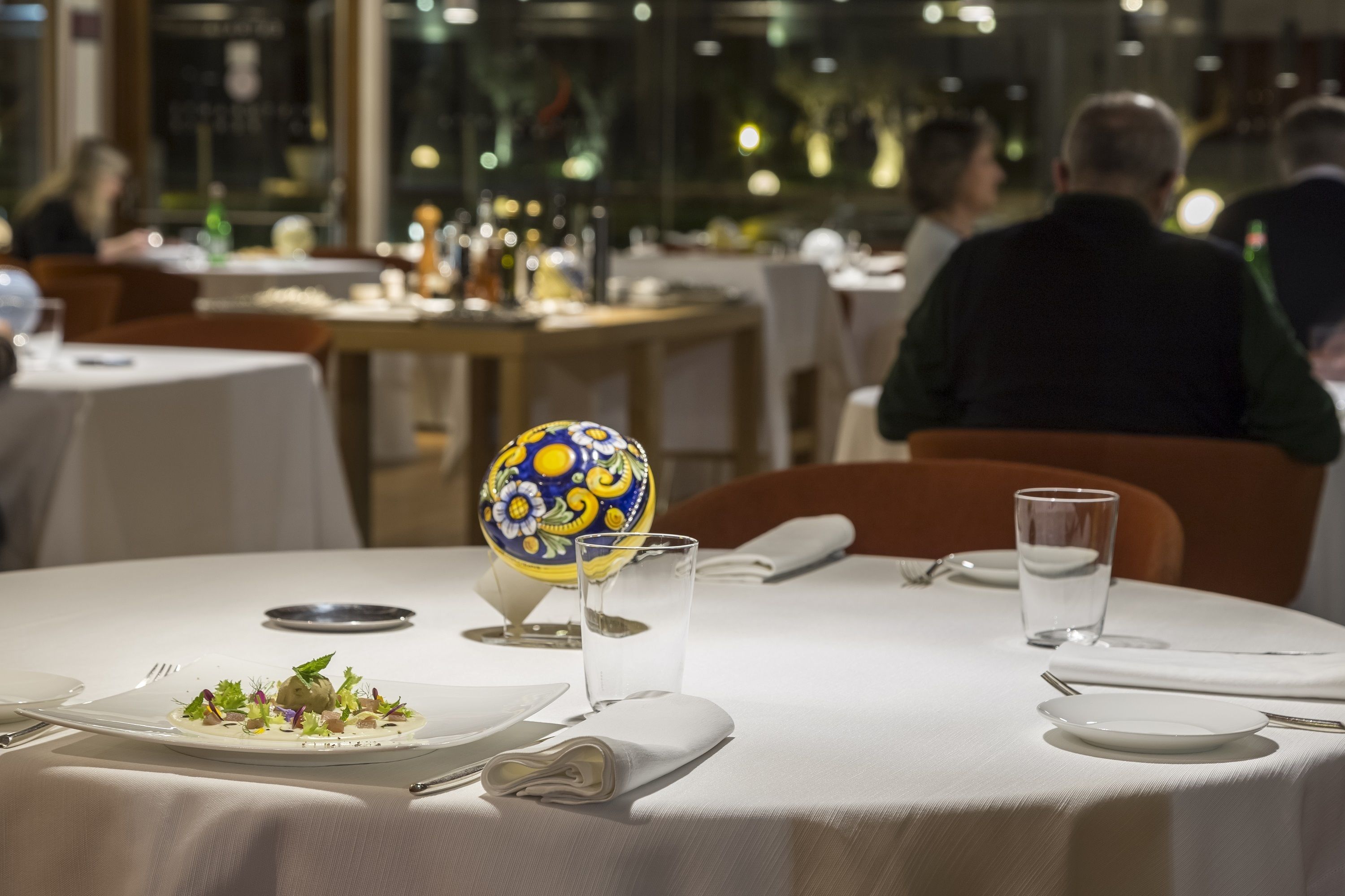 A restaurant setting with tables set for dining, including plates, glasses, and cutlery.