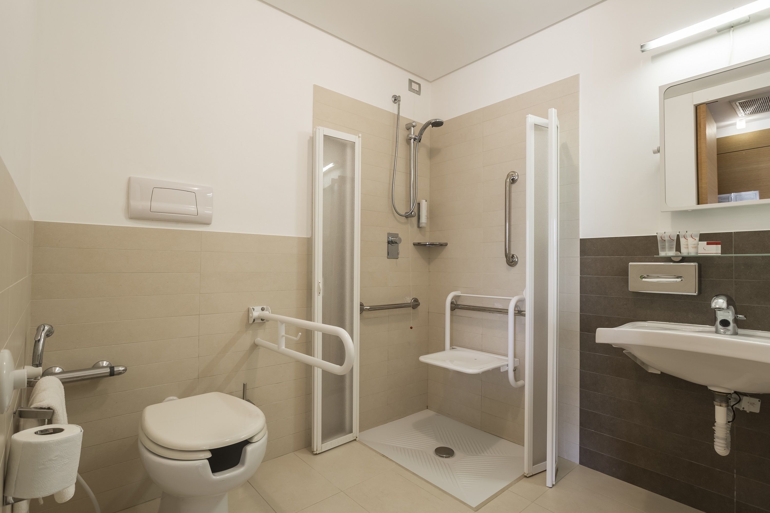 Un baño accesible para sillas de ruedas, con ducha, inodoro y lavamanos.