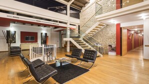 Un vestíbulo amplio con techo alto, una escalera y una zona de estar con sillas modernas y una mesa de centro.