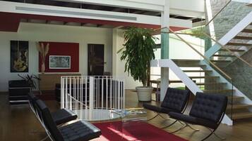 A modern interior with a staircase, seating area, and a potted plant.