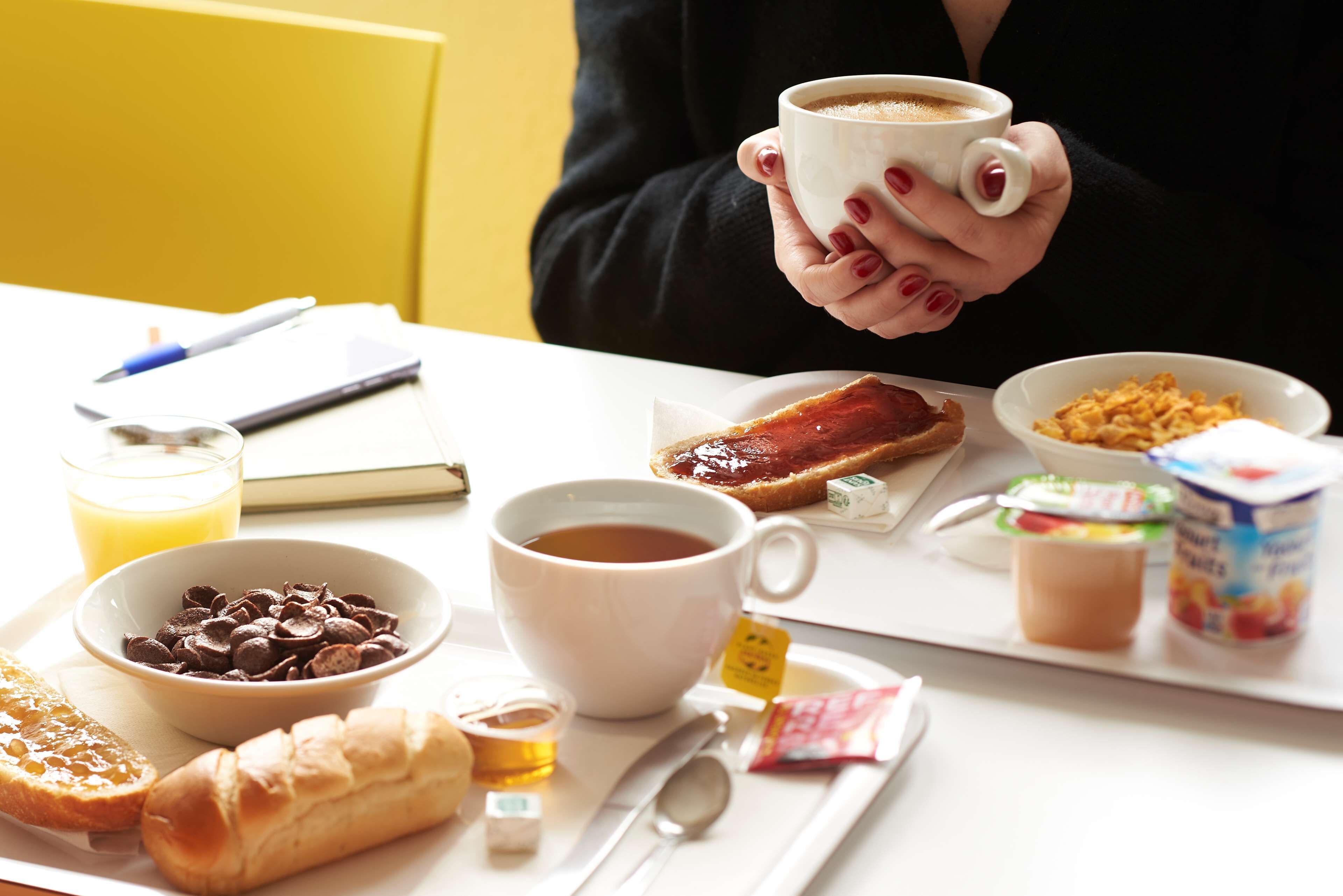 Bandeja de desayuno con café, croissant, chips de chocolate, mermelada, yogur y jugo.