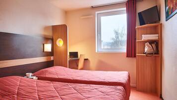 Una habitación de hotel con una cama grande, un escritorio, una silla, un televisor y un armario.