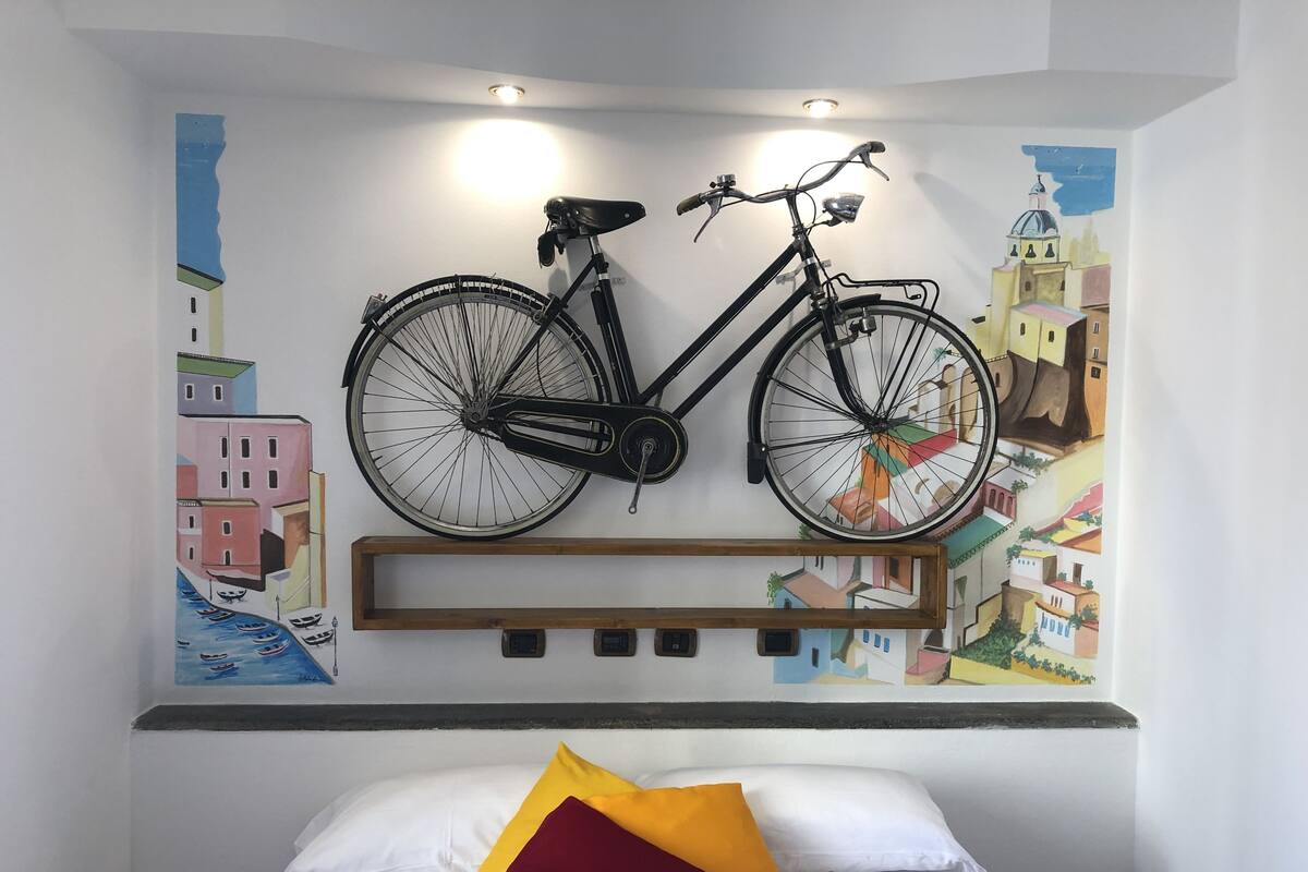 Une pièce avec un lit, un vélo fixé au mur et des peintures murales colorées.
