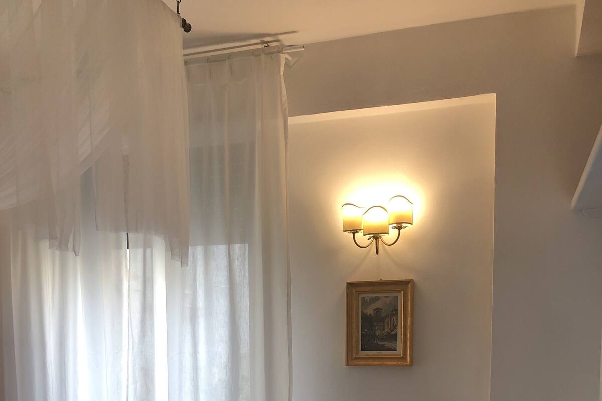 Une chambre d’hôtel avec un lit, un luminaire fixé au mur et un tableau encadré.