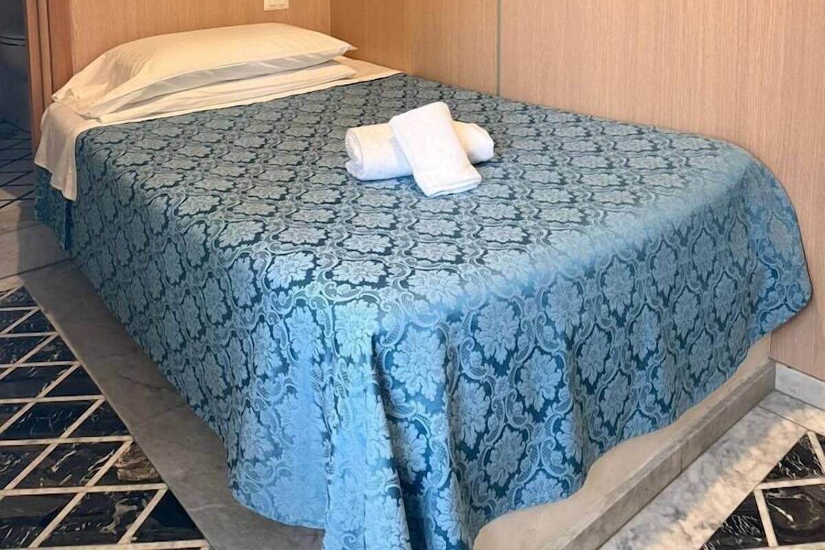 Une chambre d’hôtel avec un lit, une fresque représentant un jardin et un sol carrelé.